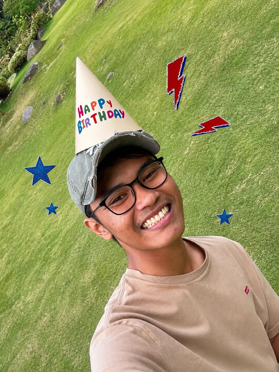 Adit memakai topi ulang tahun di taman